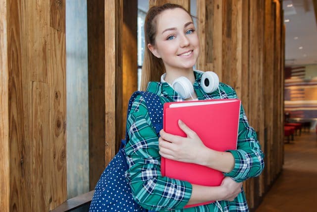 A female student holding books in hand with a bag in the library room