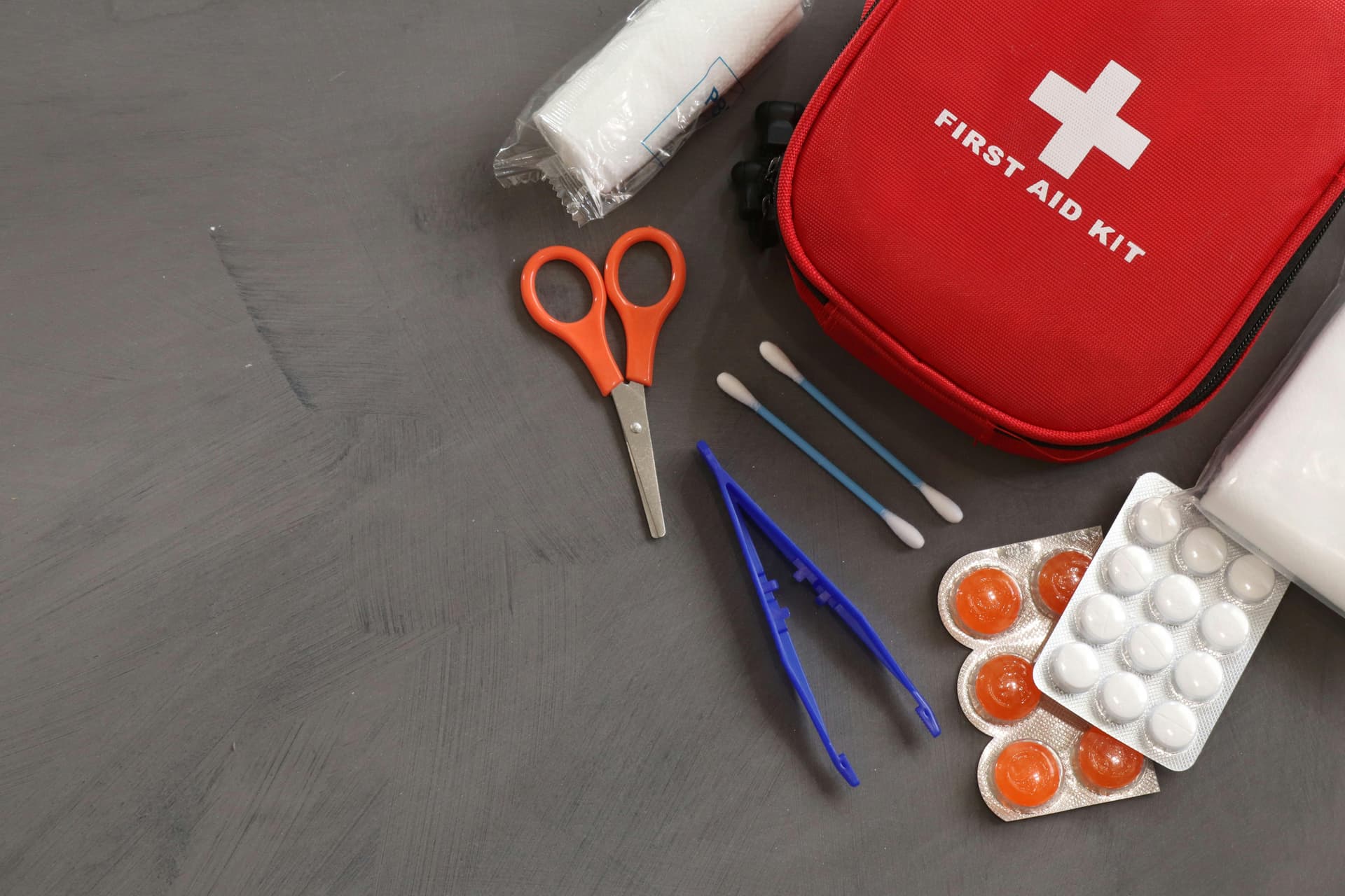 First aid kit on a table with scissors and various medical supplies arranged neatly around it.